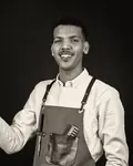 Portrait of Yusuf, smiling, in a canvas barber’s apron