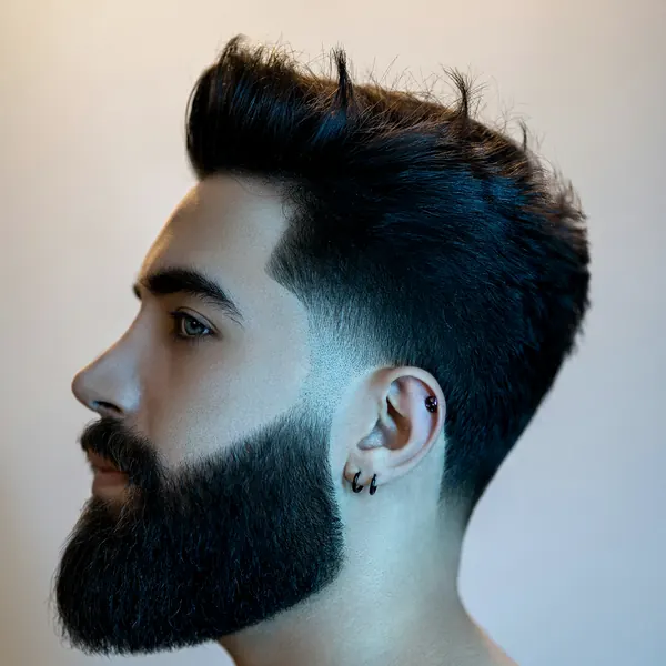 Profile of a man with a textured quiff and a sculpted full beard