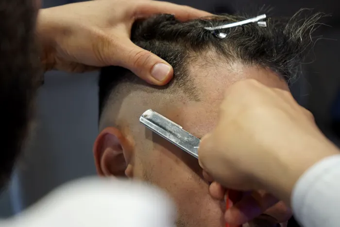 Barber cleaning up a fade line with a straight razor